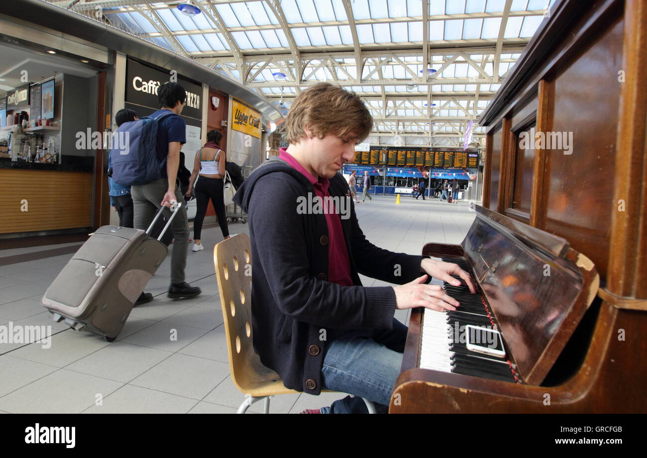 Un hombre toca el piano de la calle de la explanada de la estación de tren  de Sheffield en el centro de la ciudad de Sheffield, Yorkshire, Reino Unido  Fotografía de stock -