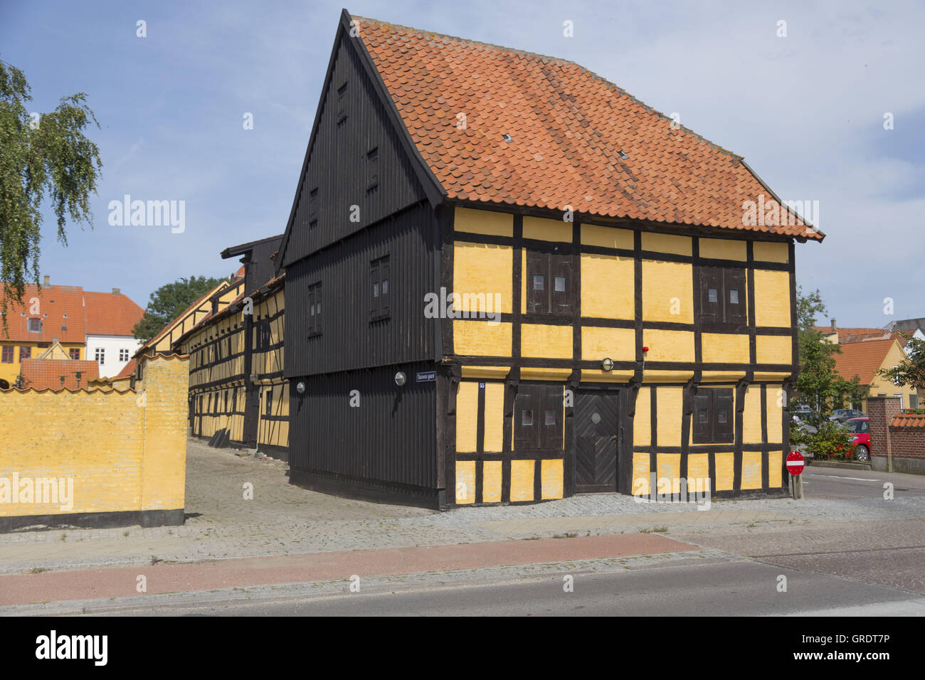 Casa Half-Timbered pintadas en amarillo en la esquina de una calle en Nakskov Dinamarca Foto de stock