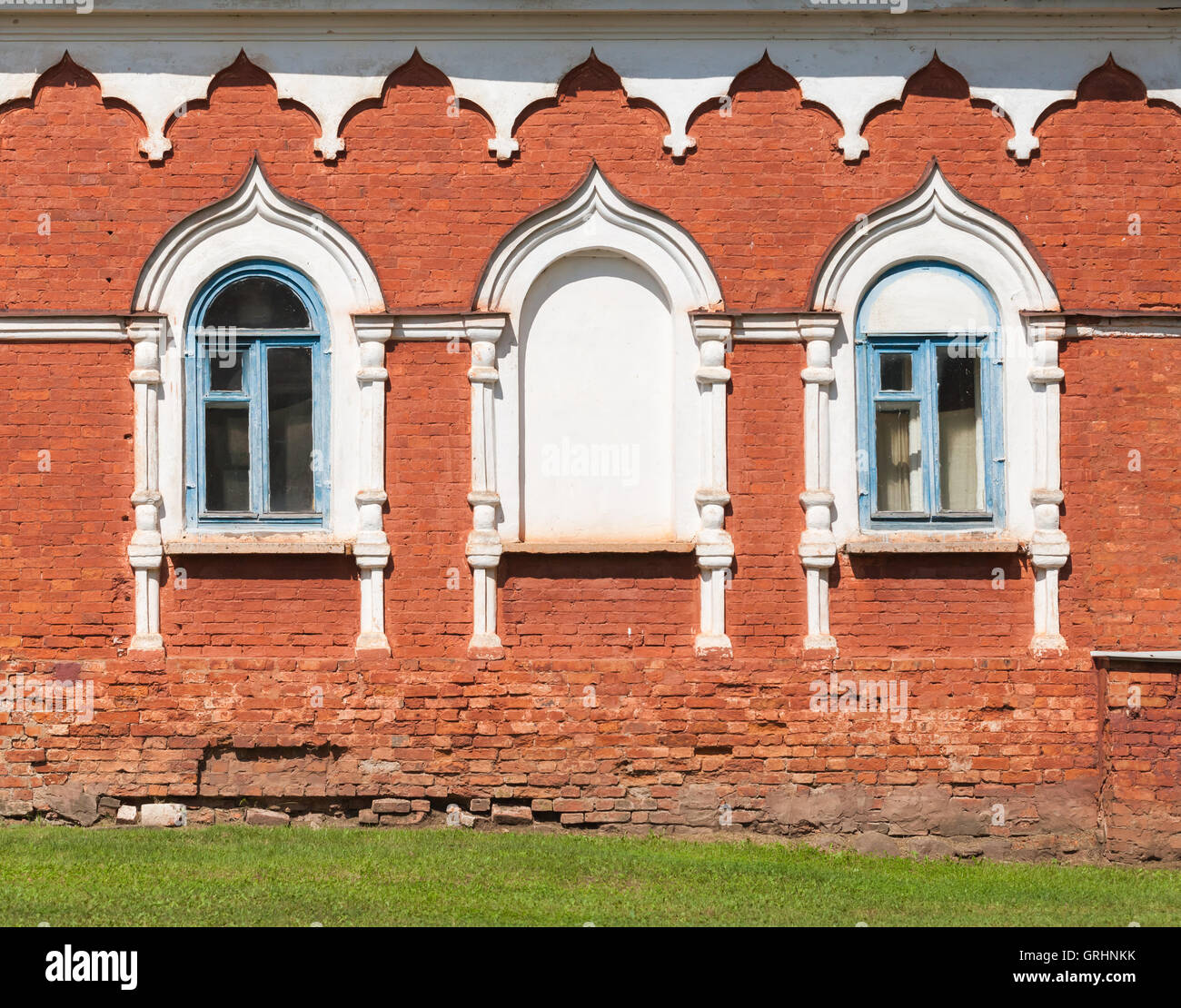 Pared de ladrillo rojo con ventanas en blanco marcos decorativos. Detalles de la arquitectura tradicional rusa antigua Foto de stock