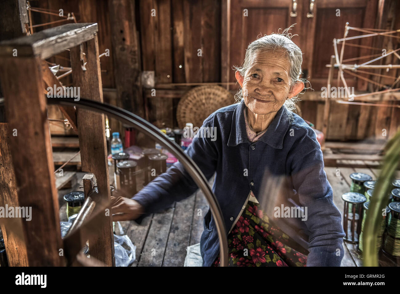 Mujer trabajadora que teje la tela en una fábrica de tejidos en el Lago Inle Foto de stock
