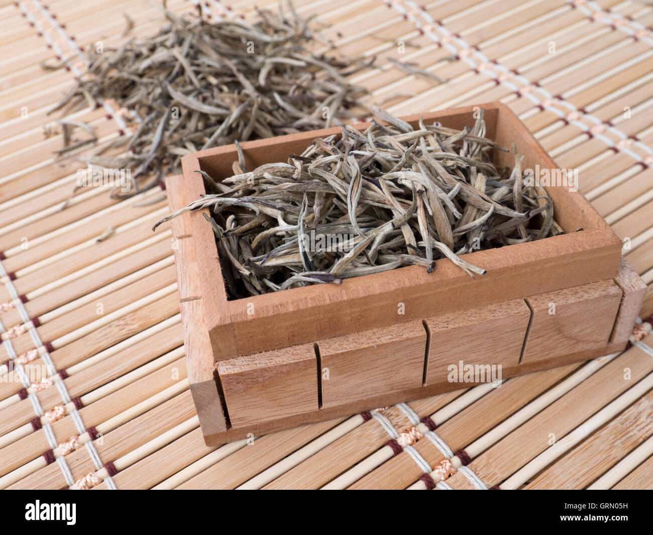 Puntas de plata té blanco en la caja de madera en la estera de bambú Foto de stock