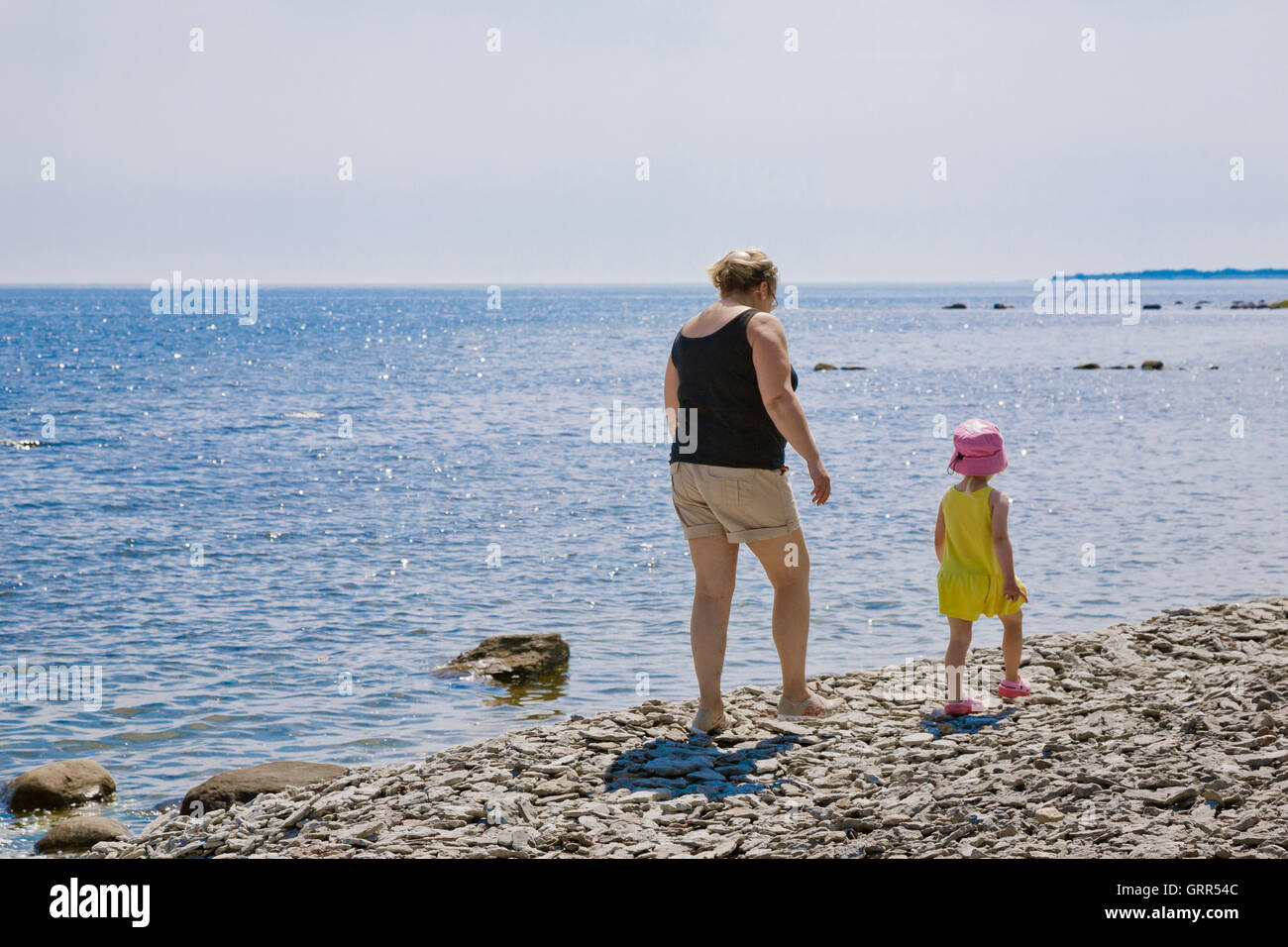 Abuela y niños caminando por una playa de cantos rodados de piedra en la isla de Gotland, SUECIA Foto de stock