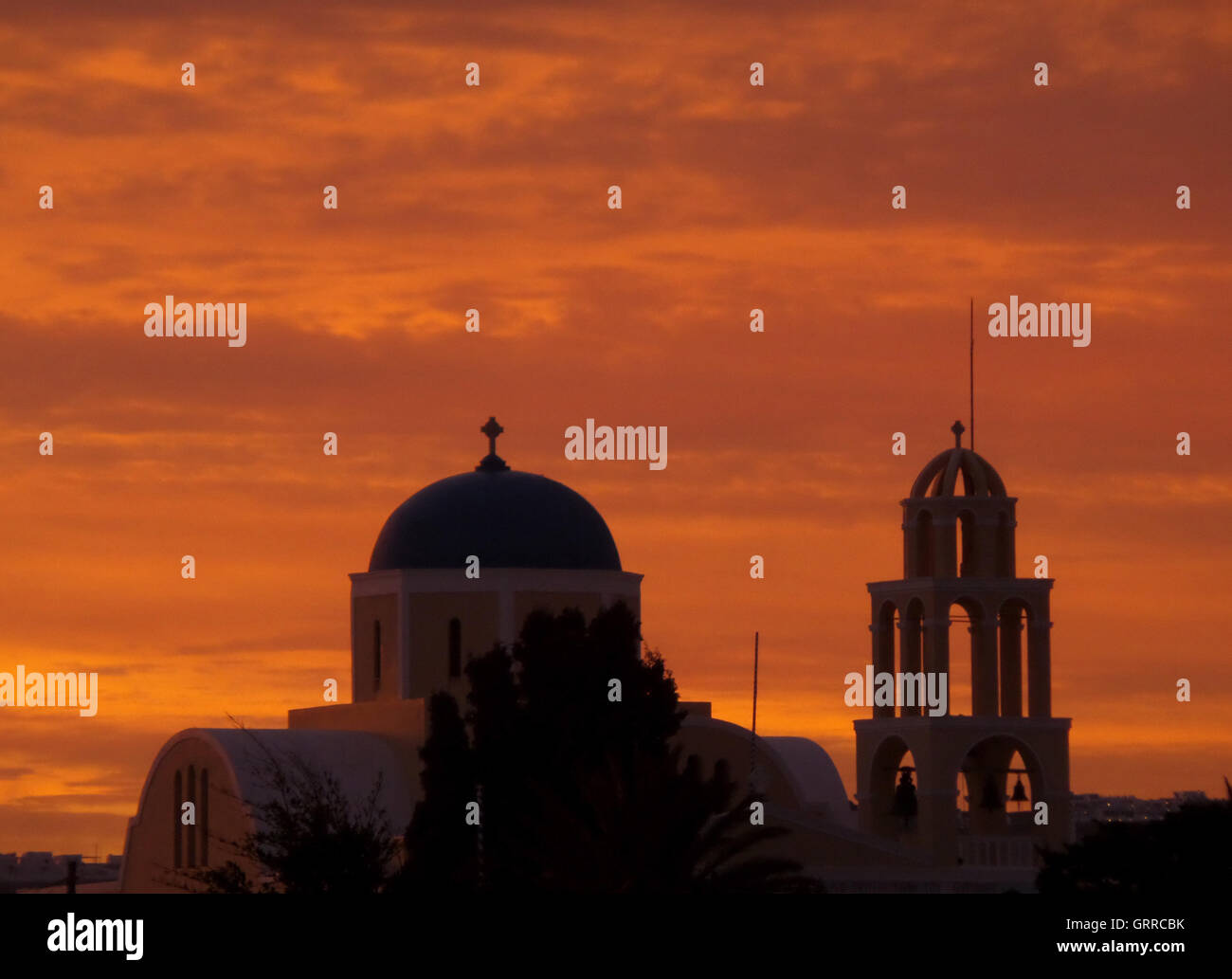 Impresionante gradación de color naranja de la posluminiscencia del atardecer sobre una iglesia en Santorini, Grecia Foto de stock