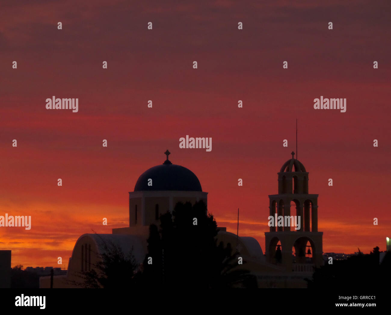 Hermoso atardecer naranja y púrpura Posluminiscencia sobre Iglesia de estilo de Cyclades, Santorini, isla de Grecia Foto de stock