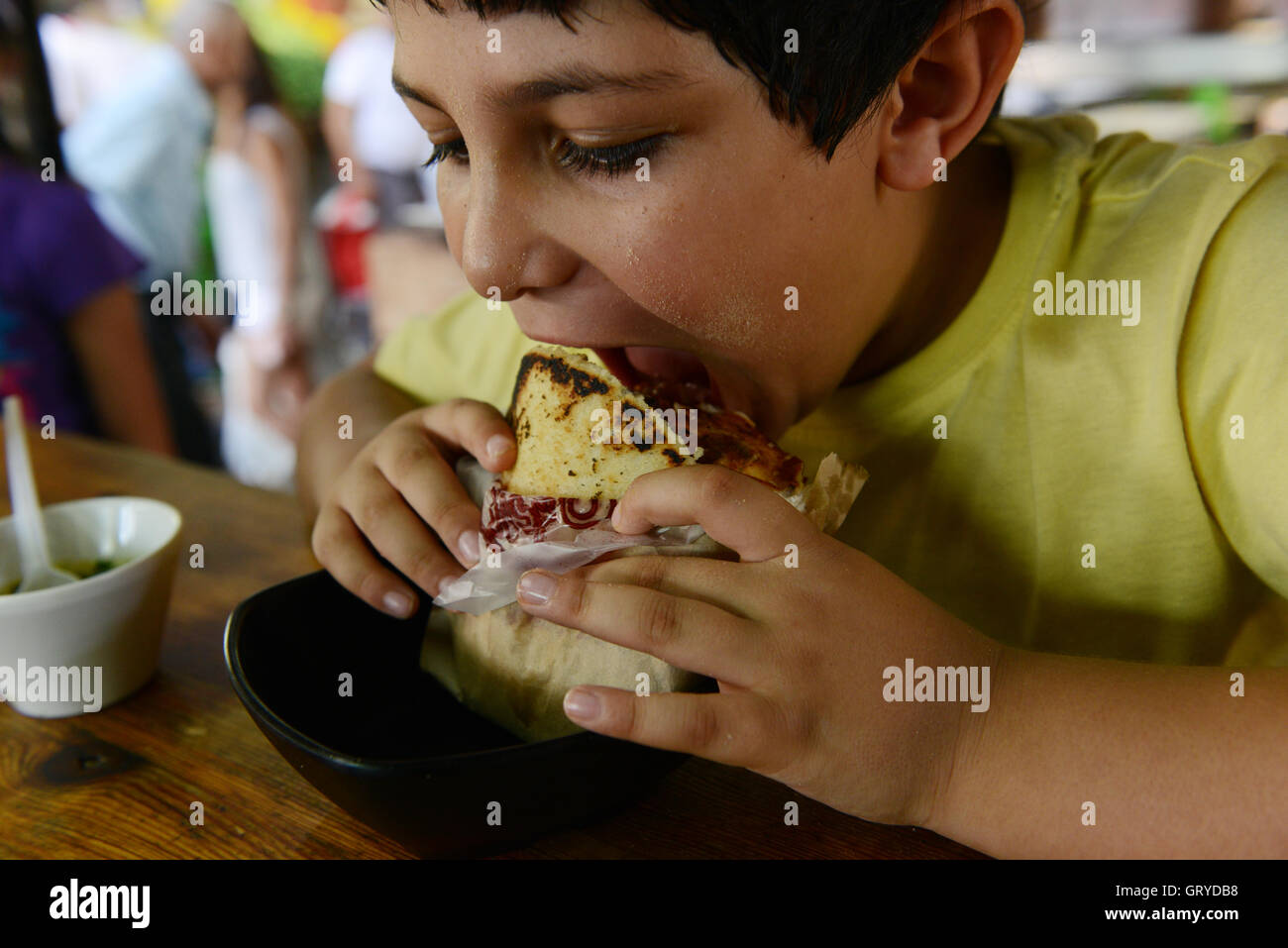 Un muchacho de comer Arepa con carne ( Arepa con carne ). Foto de stock