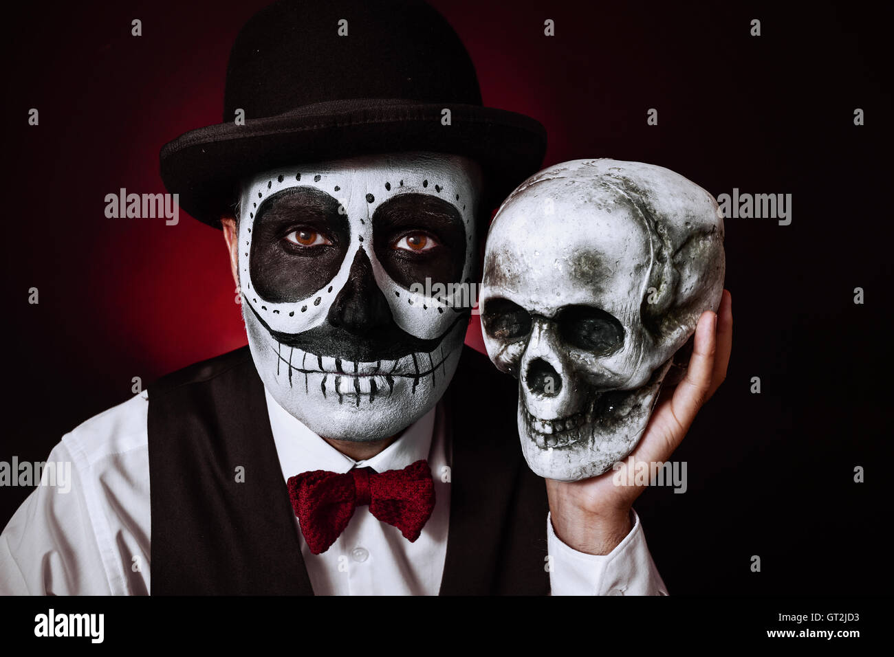 hospital cerca hielo Retrato de un hombre joven con calaveras mexicanas maquillaje, vestidos de  pajarita y sombrero, sosteniendo un cráneo en su mano junto a su Fotografía  de stock - Alamy
