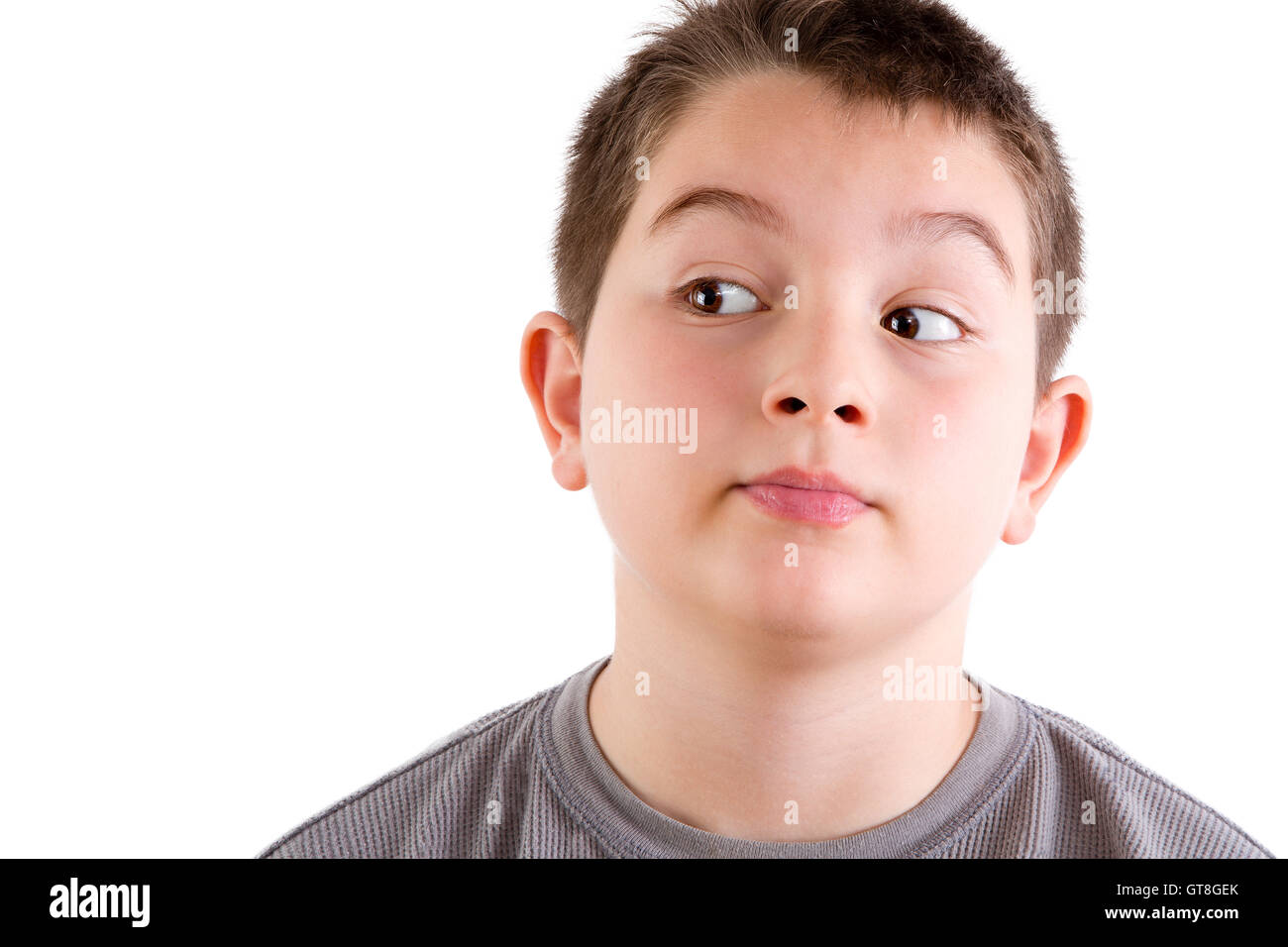 Cabeza y hombros Cerrar retrato del joven mirando hacia el lado con curiosa expresión delante de un fondo blanco con Foto de stock