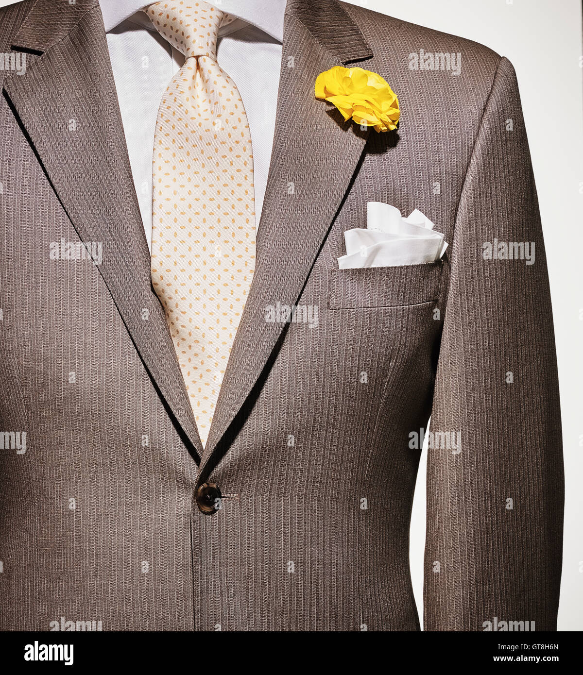 Detalle de un traje chaqueta de color marrón claro con camisa color crema y  blanco pañuelo, corbata amarillo estampado y flor amarilla Fotografía de  stock - Alamy