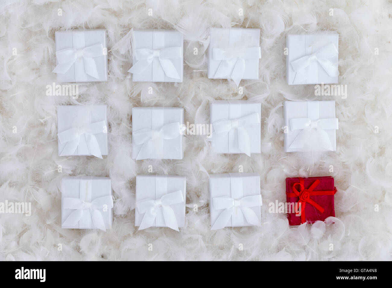 Navidad sigue la vida de uno rojo y blanco varias cajas de regalos recostados sobre un fondo de lujo de plumas blancas y suaves en un Foto de stock