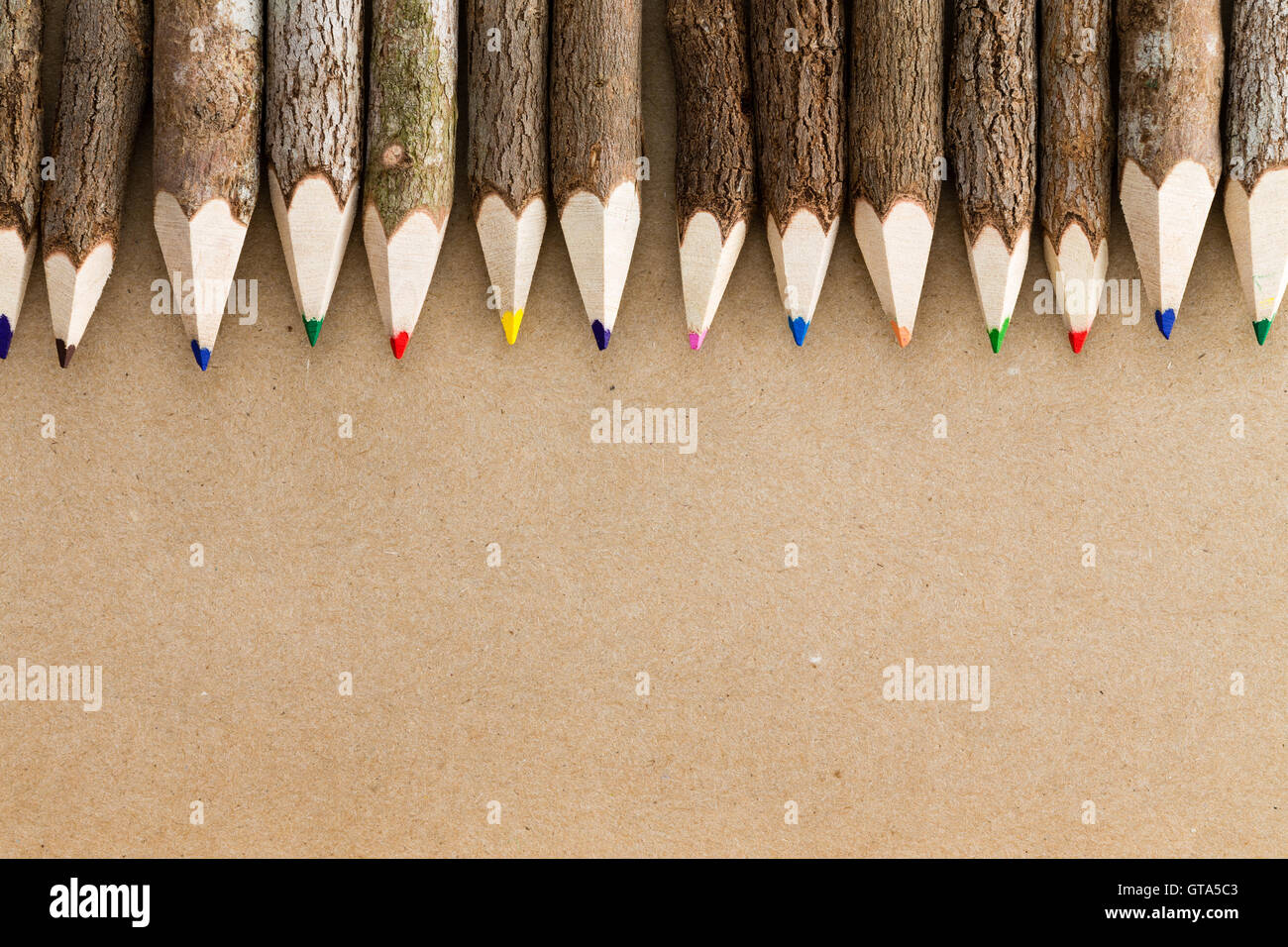 Lápiz de color madera natural divertidos crayones formando un borde  superior sobre una hoja de cartón marrón llano con espacio de copia  Fotografía de stock - Alamy