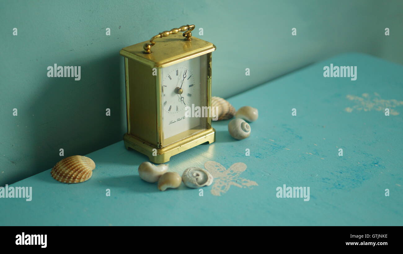 Tiempo que pasa por la orilla del mar, un carro vintage reloj rodeado por caracoles Foto de stock