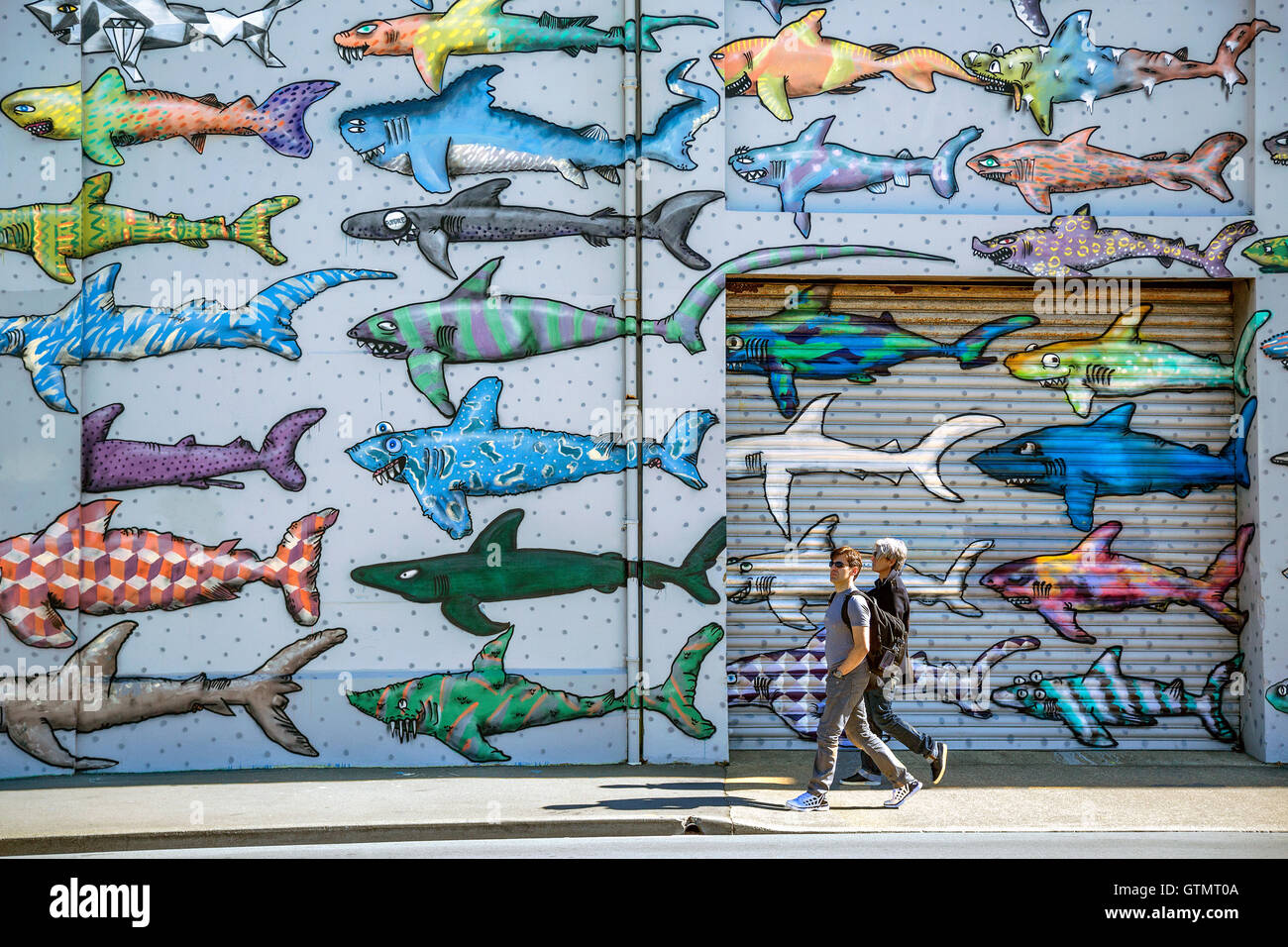 Dos adultos pasando por delante de un tiburón mural en Wellington, Nueva Zelanda Foto de stock