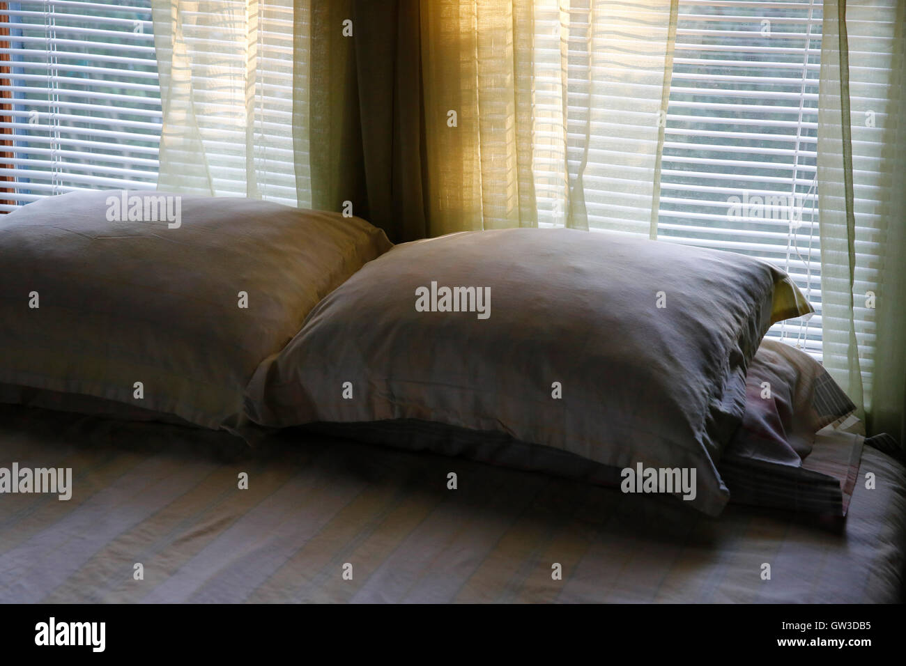 Almohadas en la cama tarde luz filtrada a través de la ventana Foto de stock