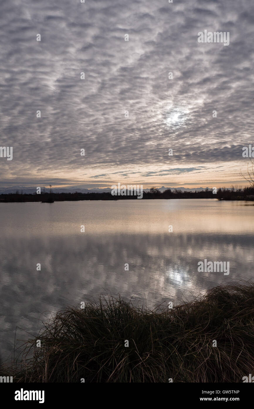 Atardecer en un lago, con el algodón como cielo nublado, Pirineos, montañas en el horizonte Foto de stock