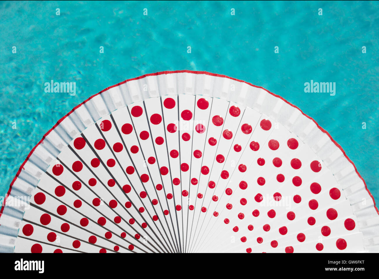 Ventilador de mano blanca (o ventilador) español con puntos rojos y el agua  de la piscina detrás Fotografía de stock - Alamy