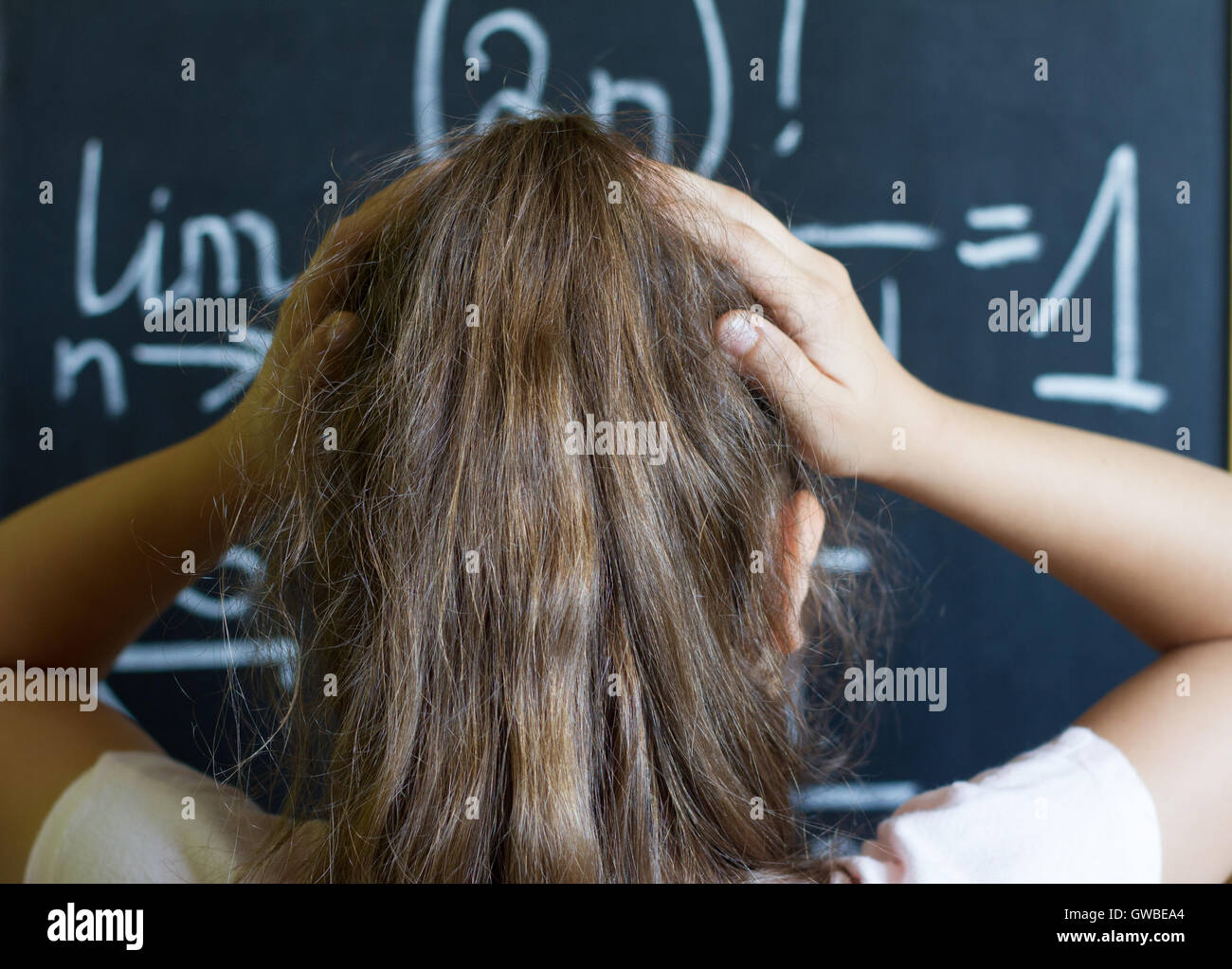 Colegiala piensa en la difícil tarea de matemáticas en la pizarra Foto de stock