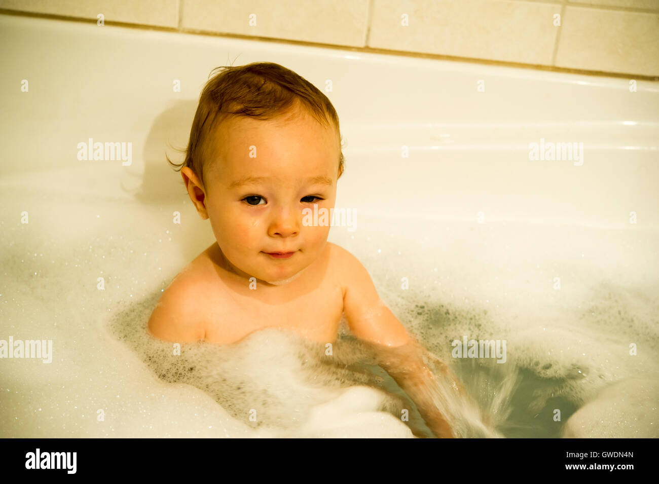 Un año viejo muchacho jugando en una bañera Foto de stock