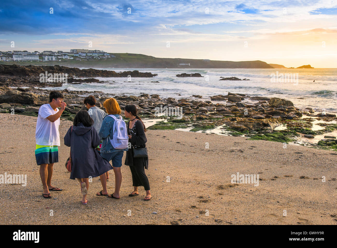 Un grupo de viajeros de pie y chatear en poco Fistral Beach en Newquay, Cornwall. Foto de stock