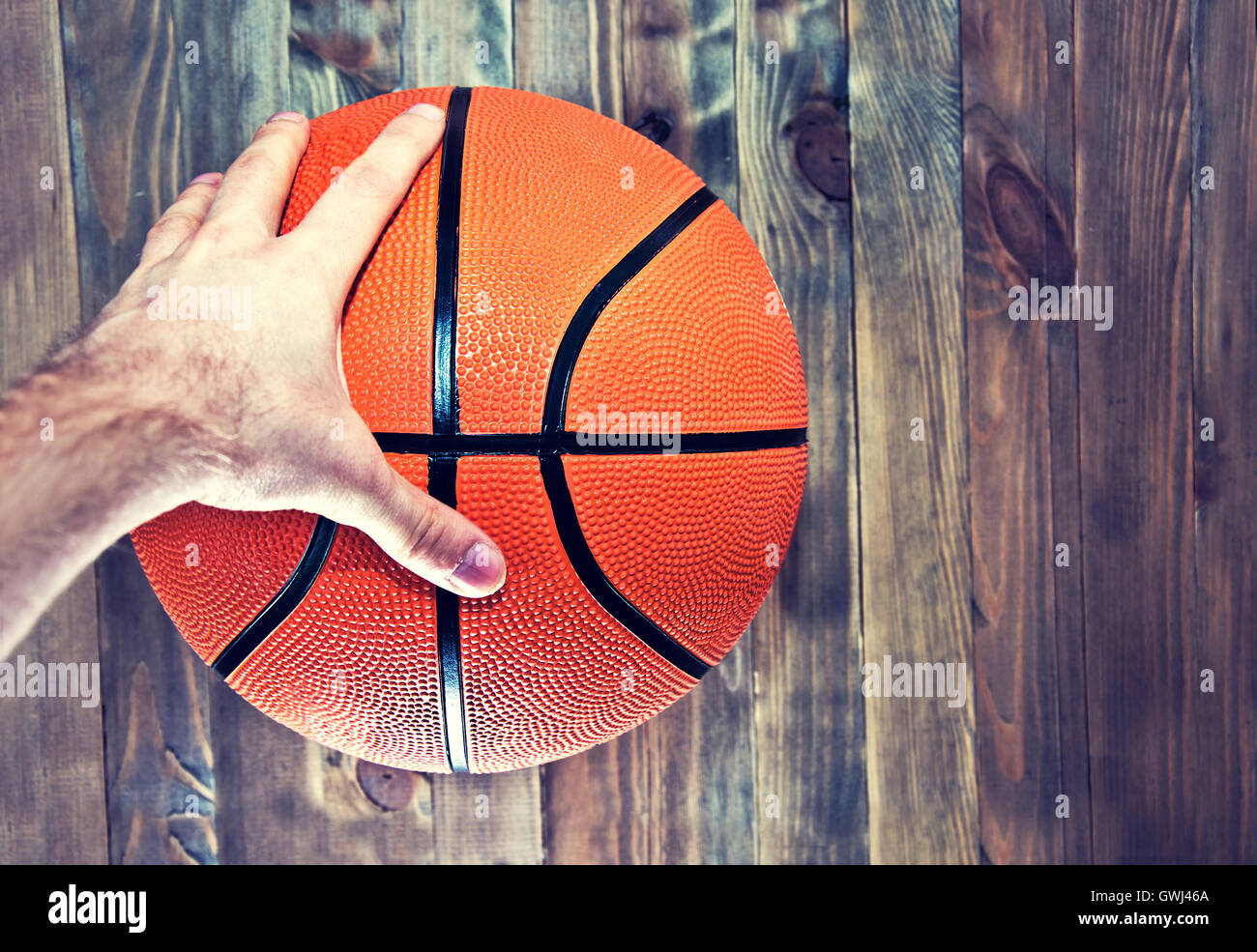 Pelota de baloncesto en el suelo de parquet de madera en la cancha de baloncesto  agarrar con la mano. Imagen Vintage Retro. Concepto de deporte Fotografía  de stock - Alamy