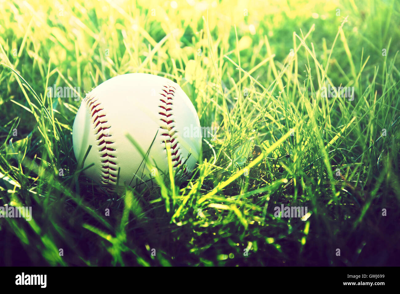 Juego de baseball. Pelota de béisbol en la hierba. Vintage Instagram fotografía. Foto de stock