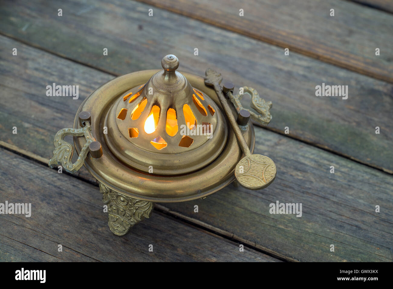 Llama en un brasero de bronce sobre la mesa de madera Foto de stock