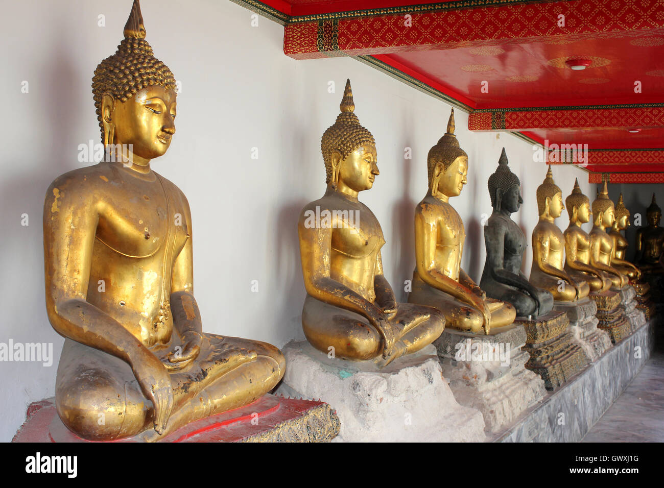 Línea de Budas sentados en el templo Wat Pho, en Bangkok, Tailandia Foto de stock