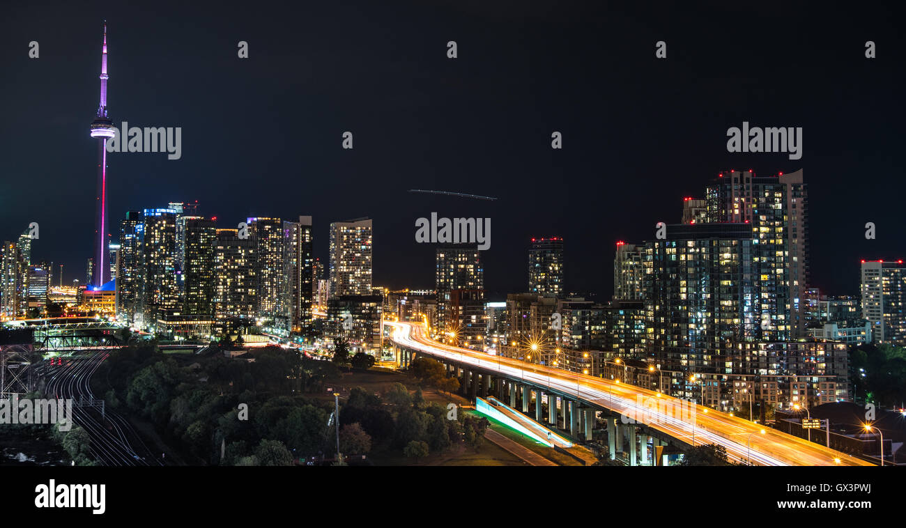 Paisaje y resplandecientes edificios como vetas de luz a lo largo de la Gardiner Expressway húmedo y caliente en una noche de verano en Toronto junto al lago. Foto de stock