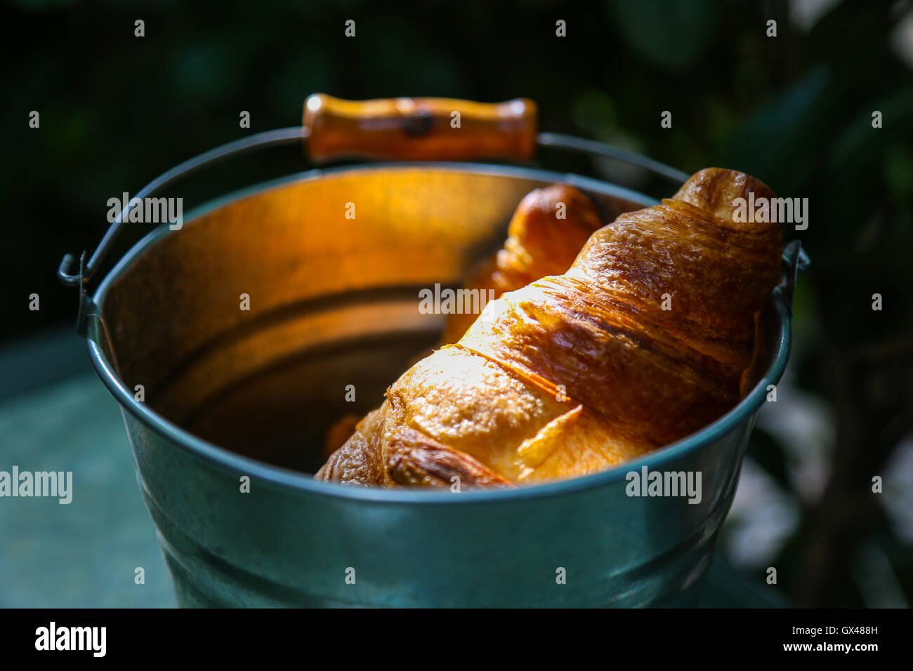 Par de croissants en una cuchara de estaño iluminadas por el sol de la mañana fuerte rayo de luz. Foto de stock