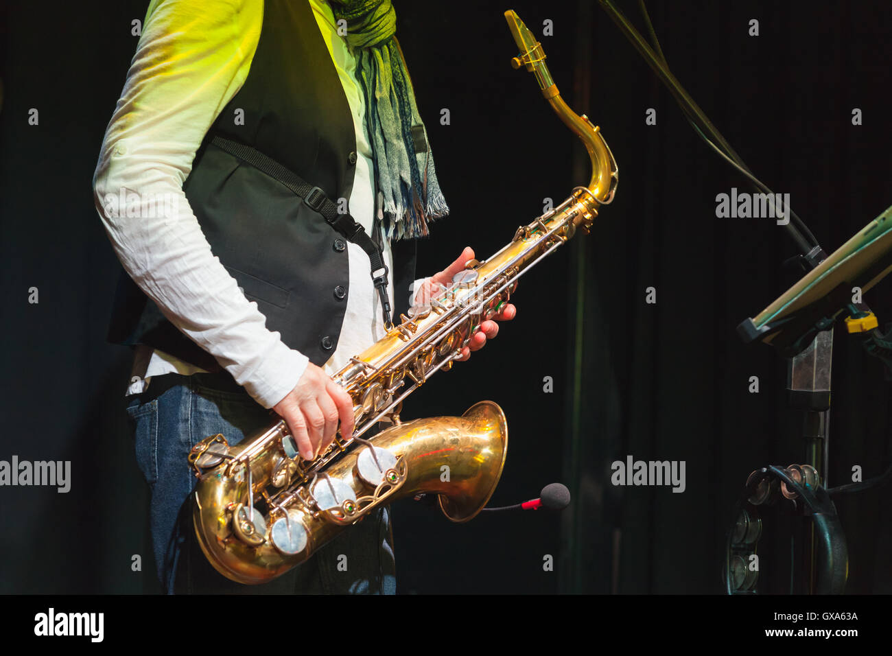Música en vivo, saxofonista en un escenario con iluminación de colores Foto de stock