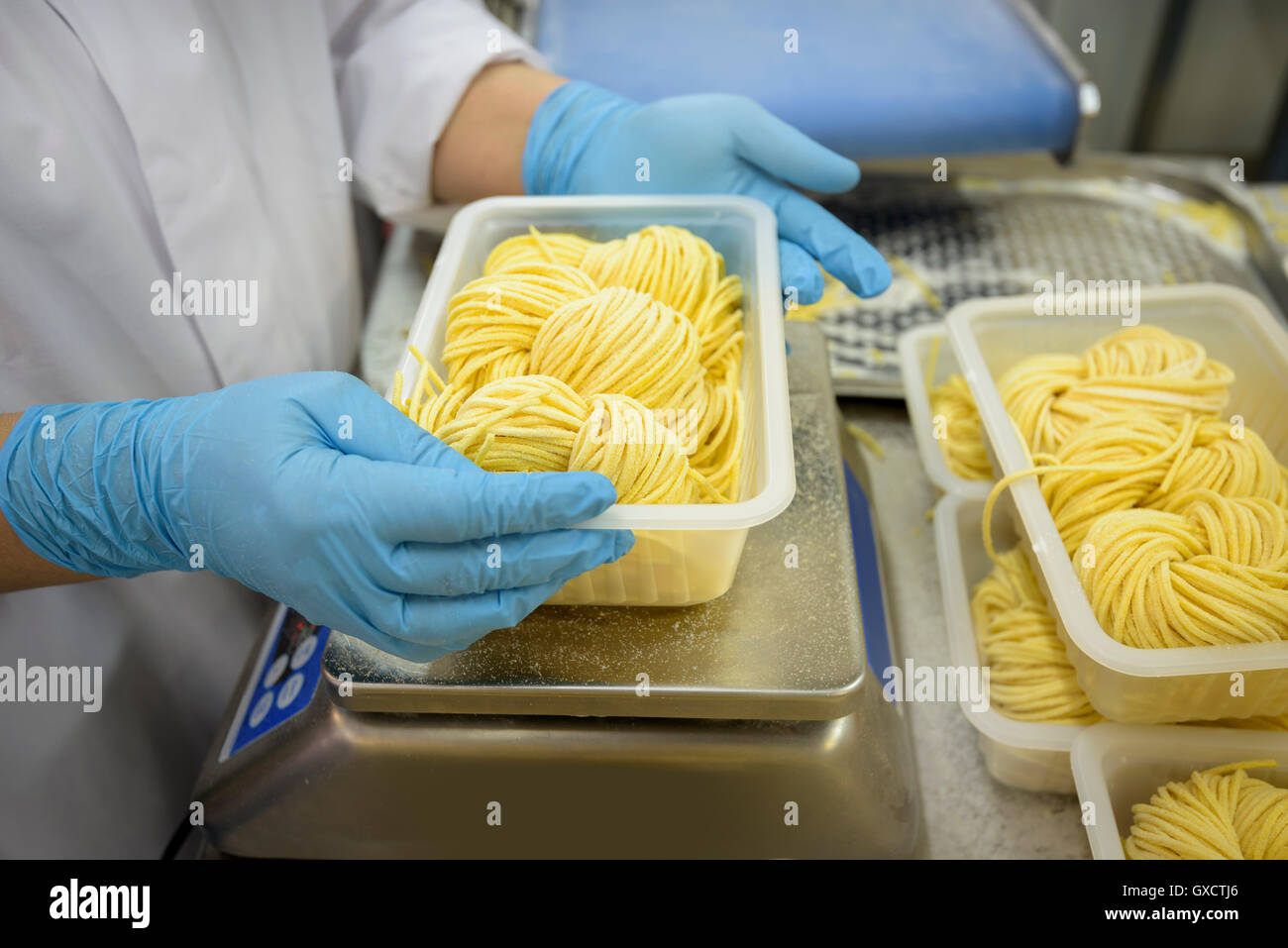 Pesaje trabajador porciones de tallarines en la fábrica de pasta, cerrar Foto de stock