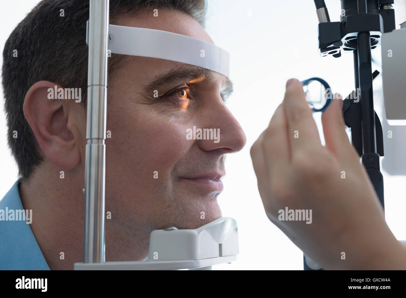 Óptico mirando a los ojos del paciente a pequeñas empresas opticas Foto de stock