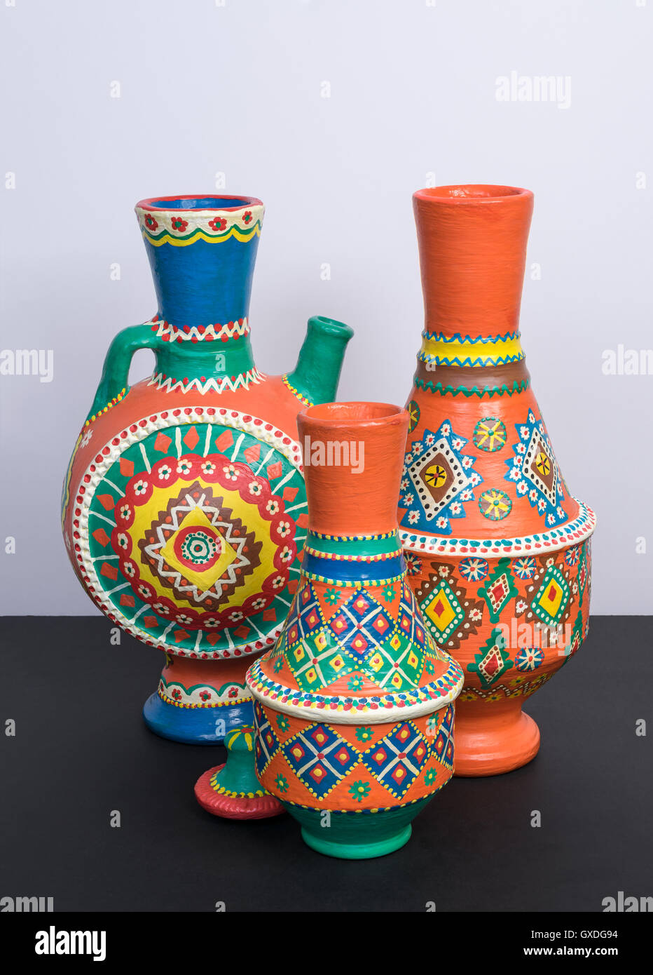 Foto de estudio de la vida de tres vasijas de cerámica ornamental naranja  sobre fondo negro de mesa y pared blanca Fotografía de stock - Alamy
