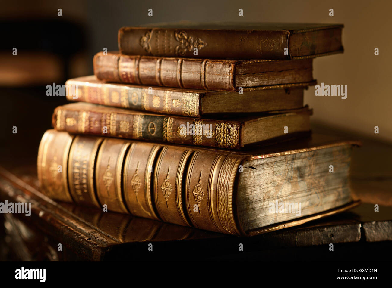 Pila de libros antiguos sobre superficie de madera antigua en la cálida luz direccional. El grunge y el enfoque selectivo. Foto de stock