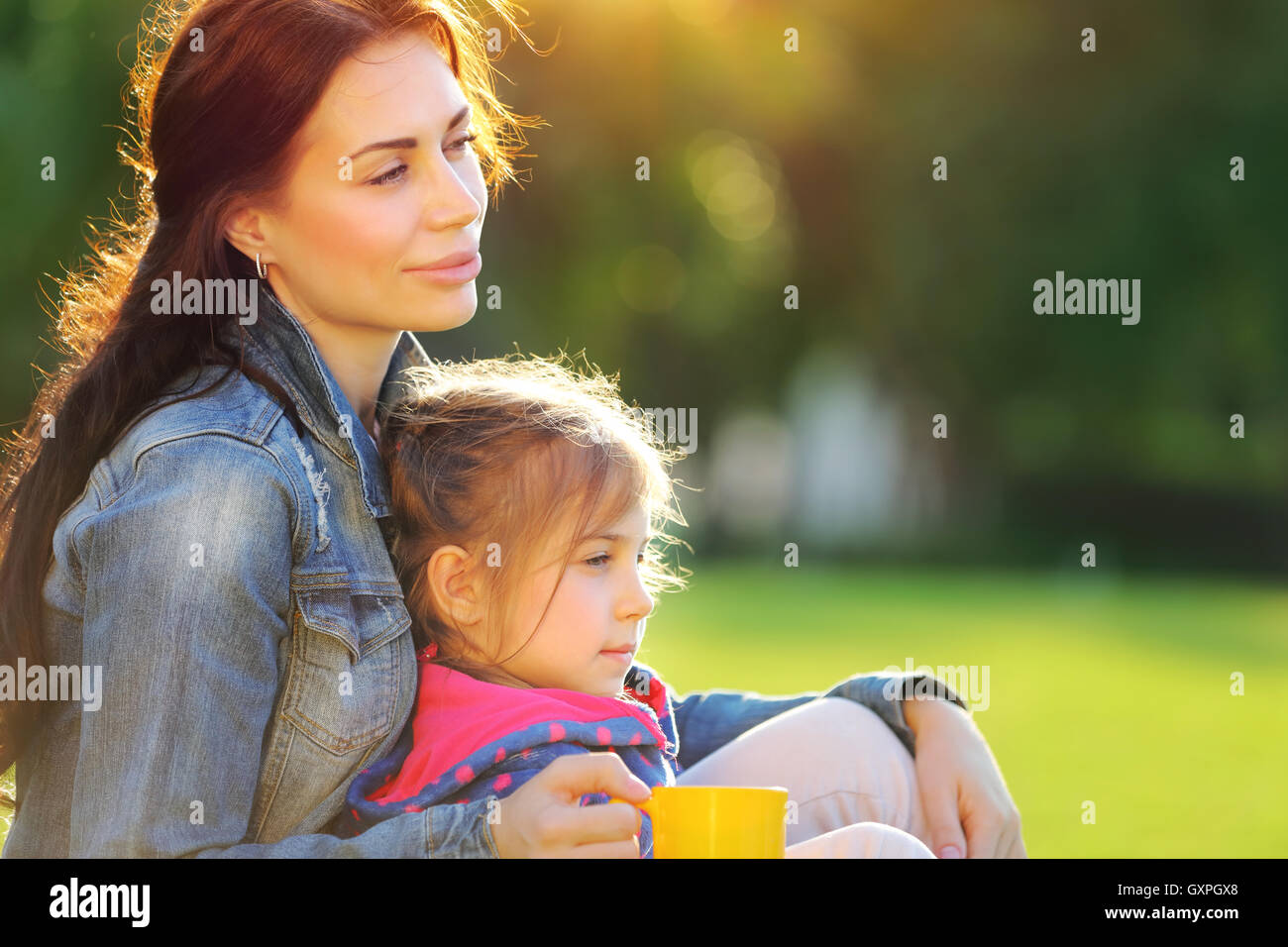Retrato de la madre con la hija de relajarse al aire libre, pasar tiempo juntos en cálidos y soleados días de otoño, amorosa familia feliz Foto de stock