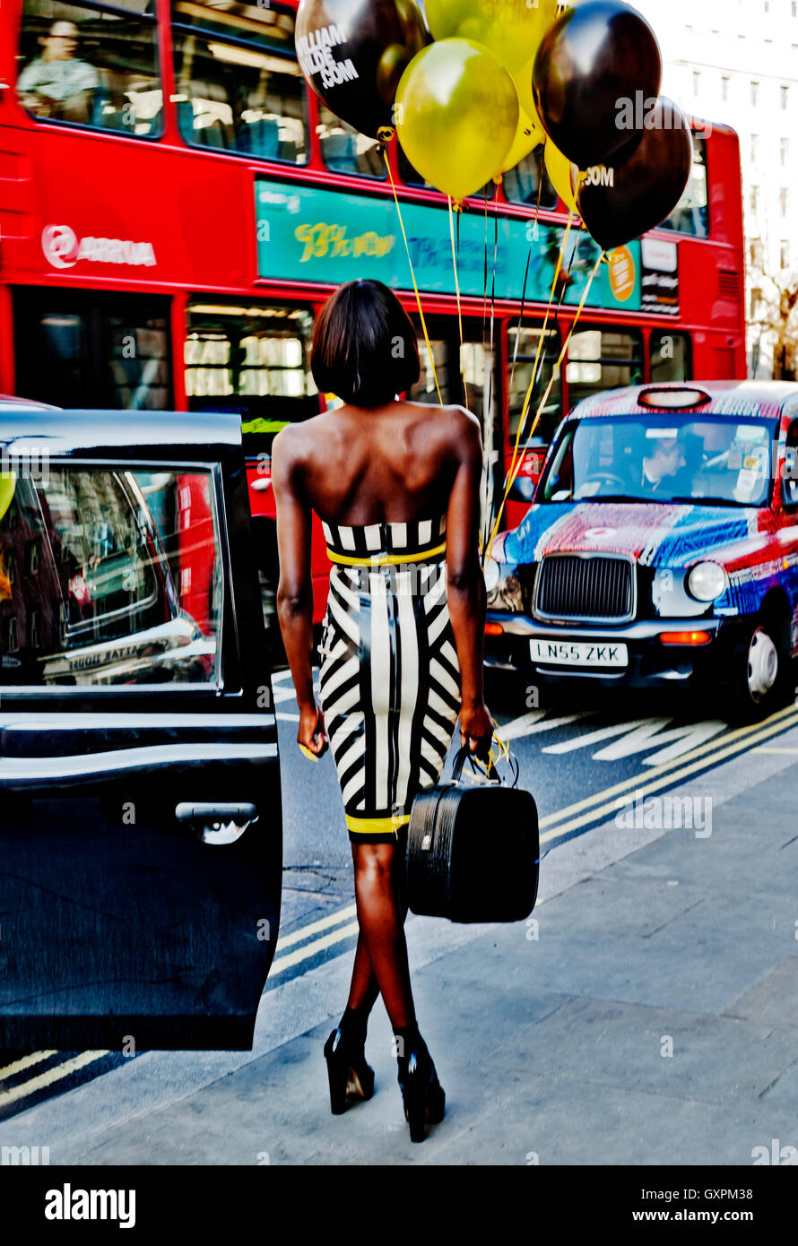 La Semana de la Moda de Londres de febrero de 2013, la moda atractiva modelo posa con globos en medio del tráfico de Londres, Londres WC2, Inglaterra, Reino Unido. Foto de stock