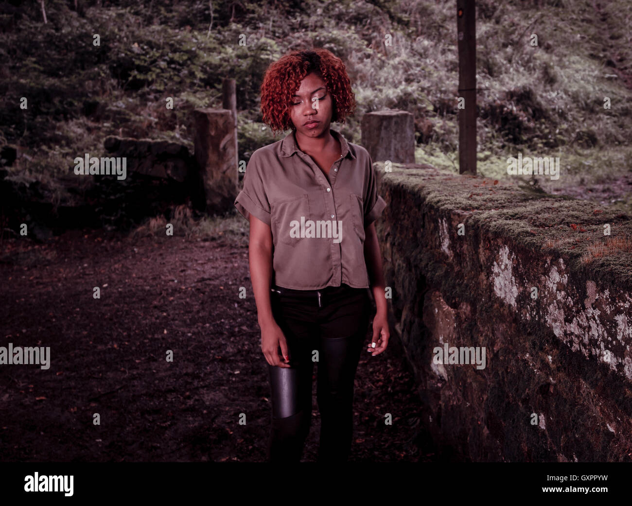 Un adolescente negro hermosas caminatas en el bosque, colores desaturados. Foto de stock