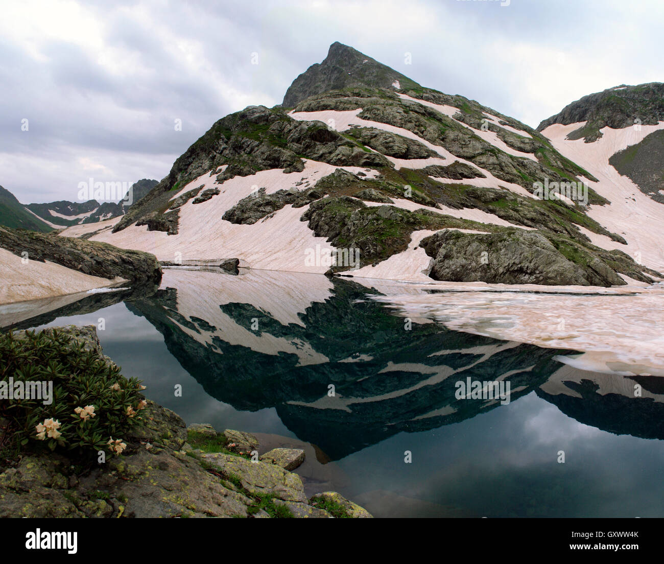 Imagen de espejo de los picos de las montañas están cubiertos de glaciares en el lago Foto de stock