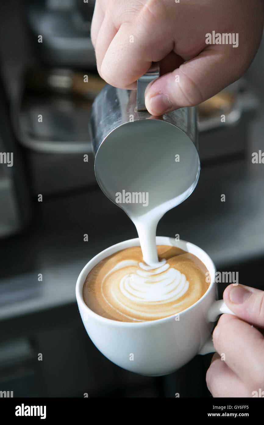 Un barista, verter la leche caliente en una taza de café fresco para hacer  un latte Fotografía de stock - Alamy