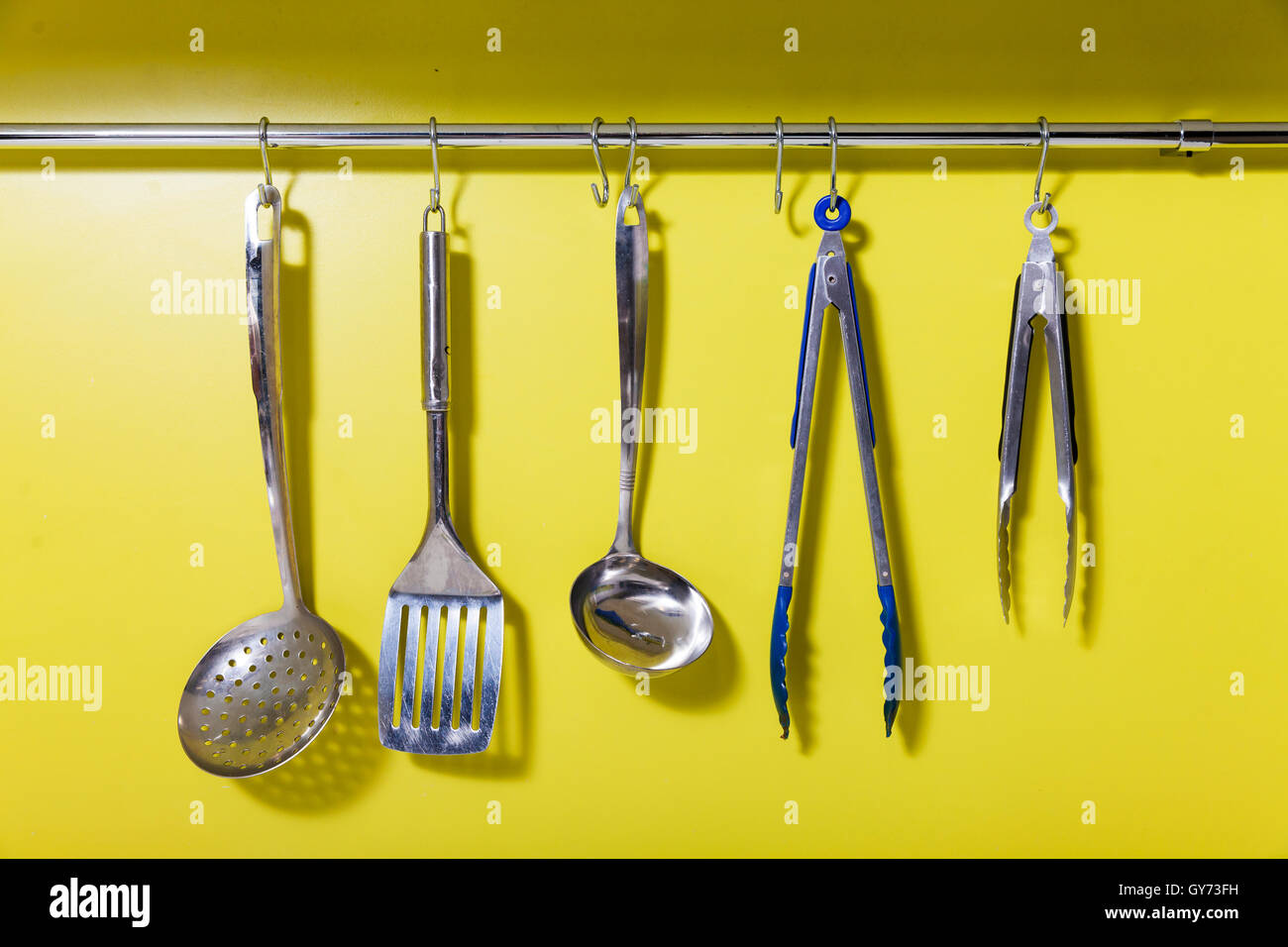 Variedad de utensilios de cocina en un colgador contra la pared de la cocina  Fotografía de stock - Alamy