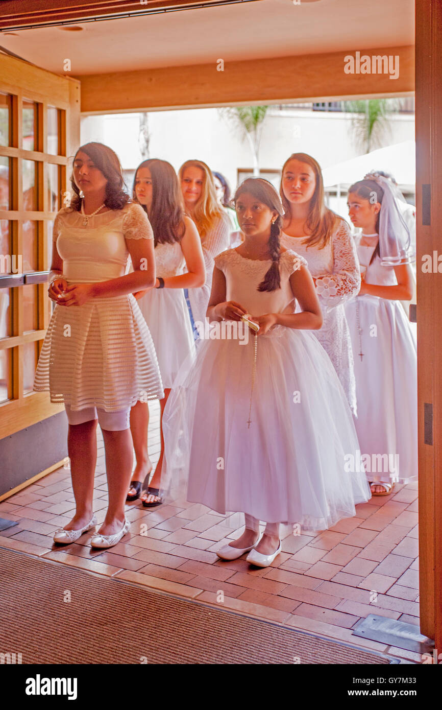 Niñas vestidos formalmente espere en la puerta de la iglesia antes de  participar en la misa de primera comunión en una Laguna Niguel, CA, Iglesia  Católica. La primera Comunión es una ceremonia