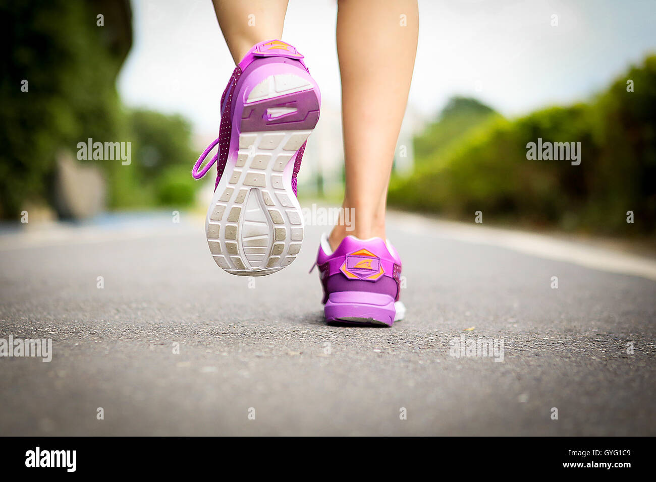 Atleta runner pies corriendo por la carretera closeup en la zapata. Mujer fitness entrenamiento jog concepto wellness. Foto de stock