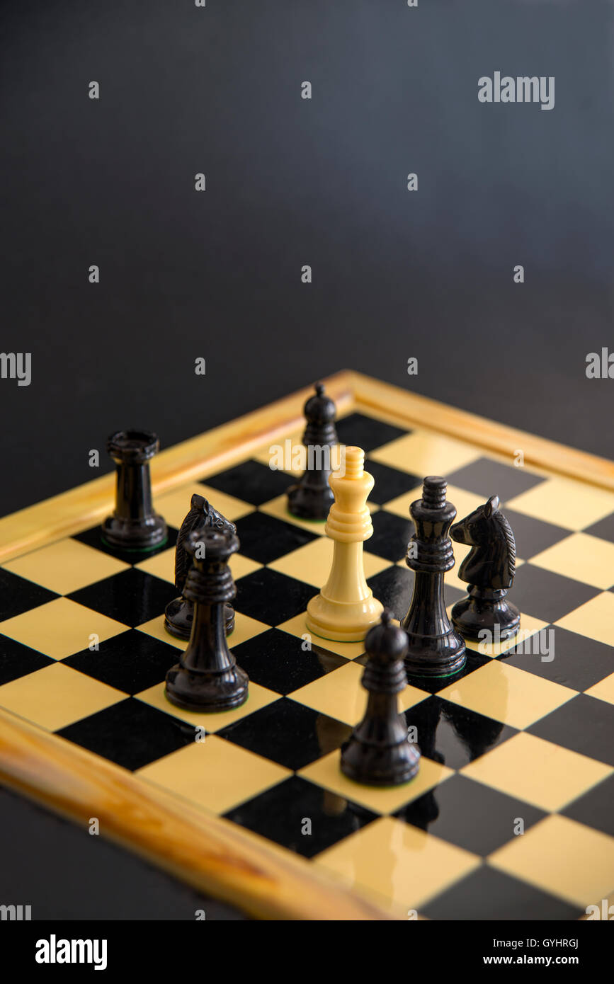 Piezas de ajedrez blanca que rodea rey negro. Cerrar vista. Foto de stock