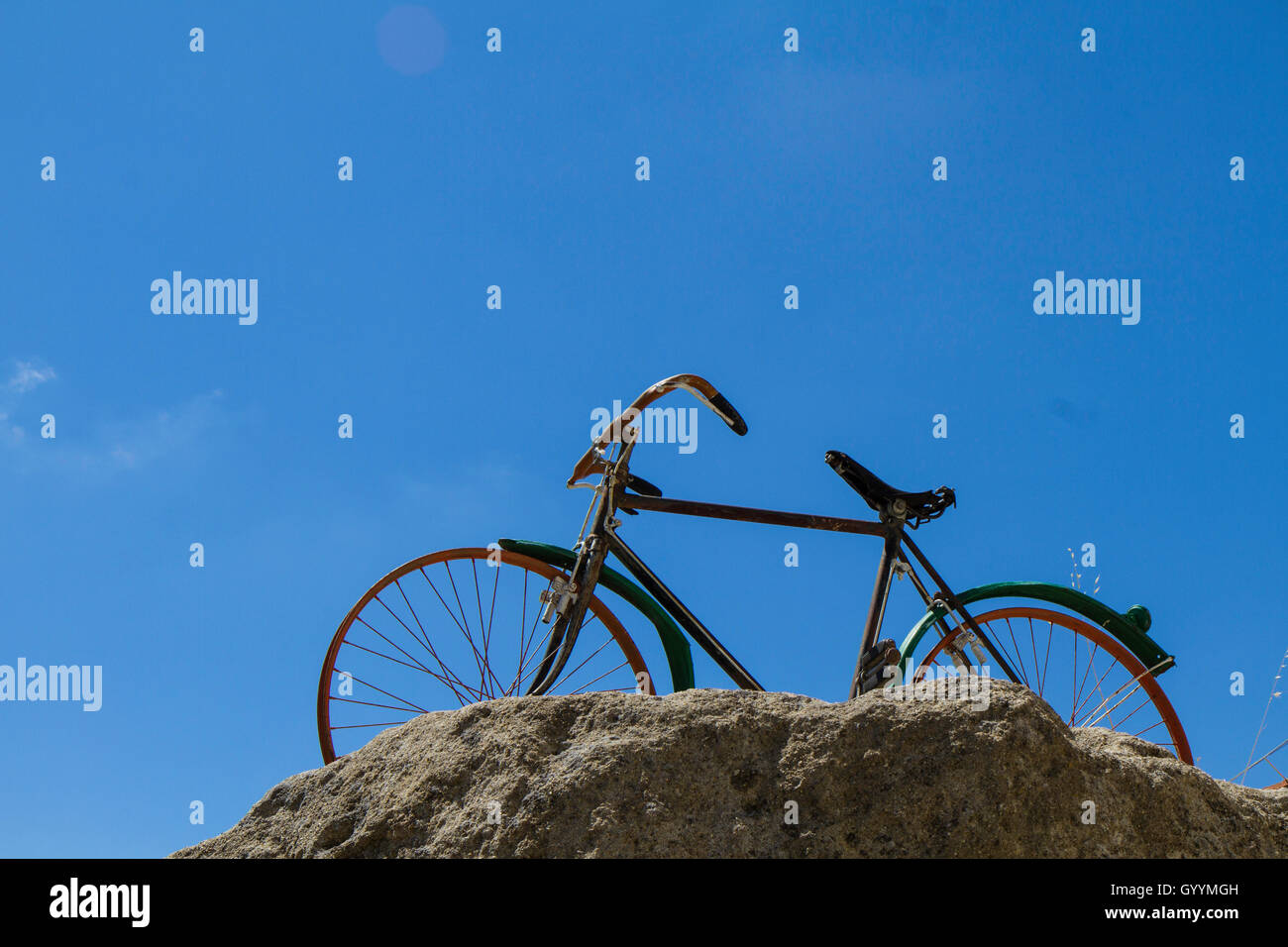 Vista inferior de la bicicleta en roca sobre fondo de cielo azul Foto de stock