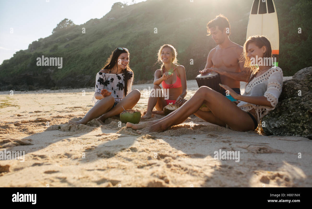Amigos felices fiestas en la playa con música y los cocos. Los jóvenes feliz divirtiéndose en la playa en un día de verano. Foto de stock