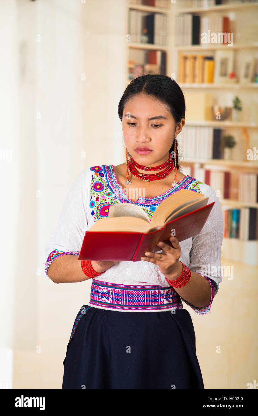 Hermosa joven llevar falda negra, blusa tradicional andina con collar, pie posando para la cámara, holding red boo Fotografía stock - Alamy