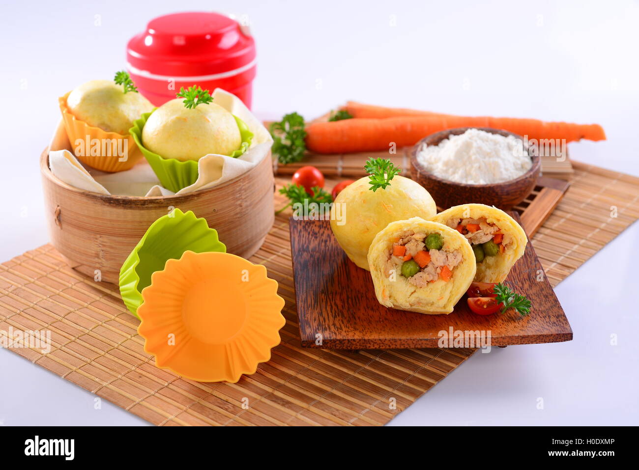 Pollo chino dumplings con la zanahoria, rodajas de tomate y hierbas en bandeja de bambú madera Foto de stock