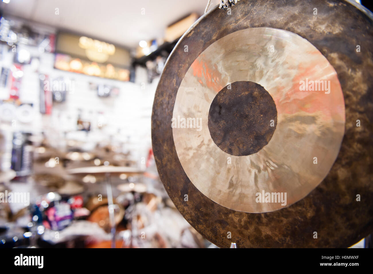 Instrumento de percusión de gong de cerca con fuera de foco drum shop en segundo plano. Foto de stock