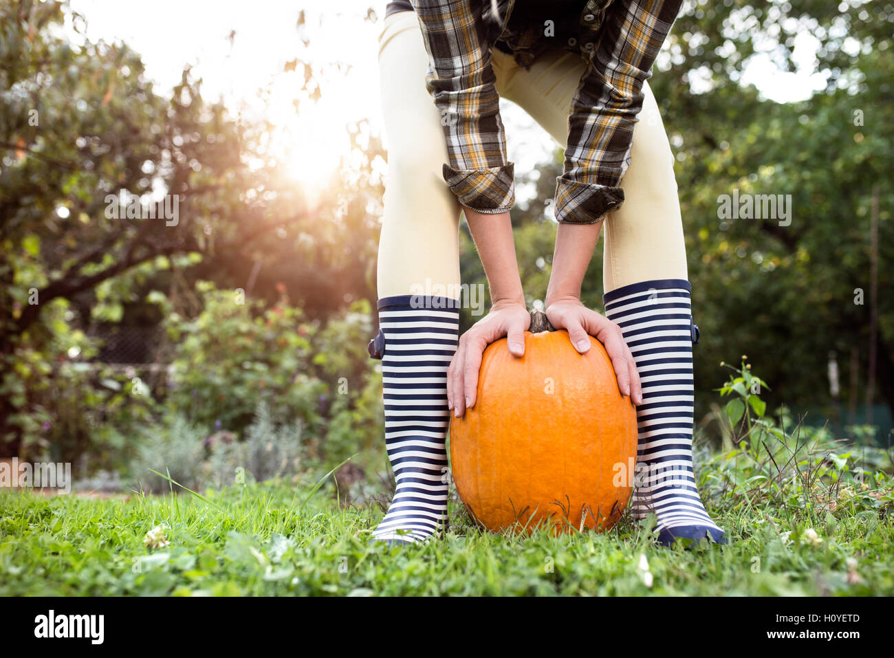 Mujer irreconocible en rayas botas de goma mantiene la bomba naranja Foto de stock