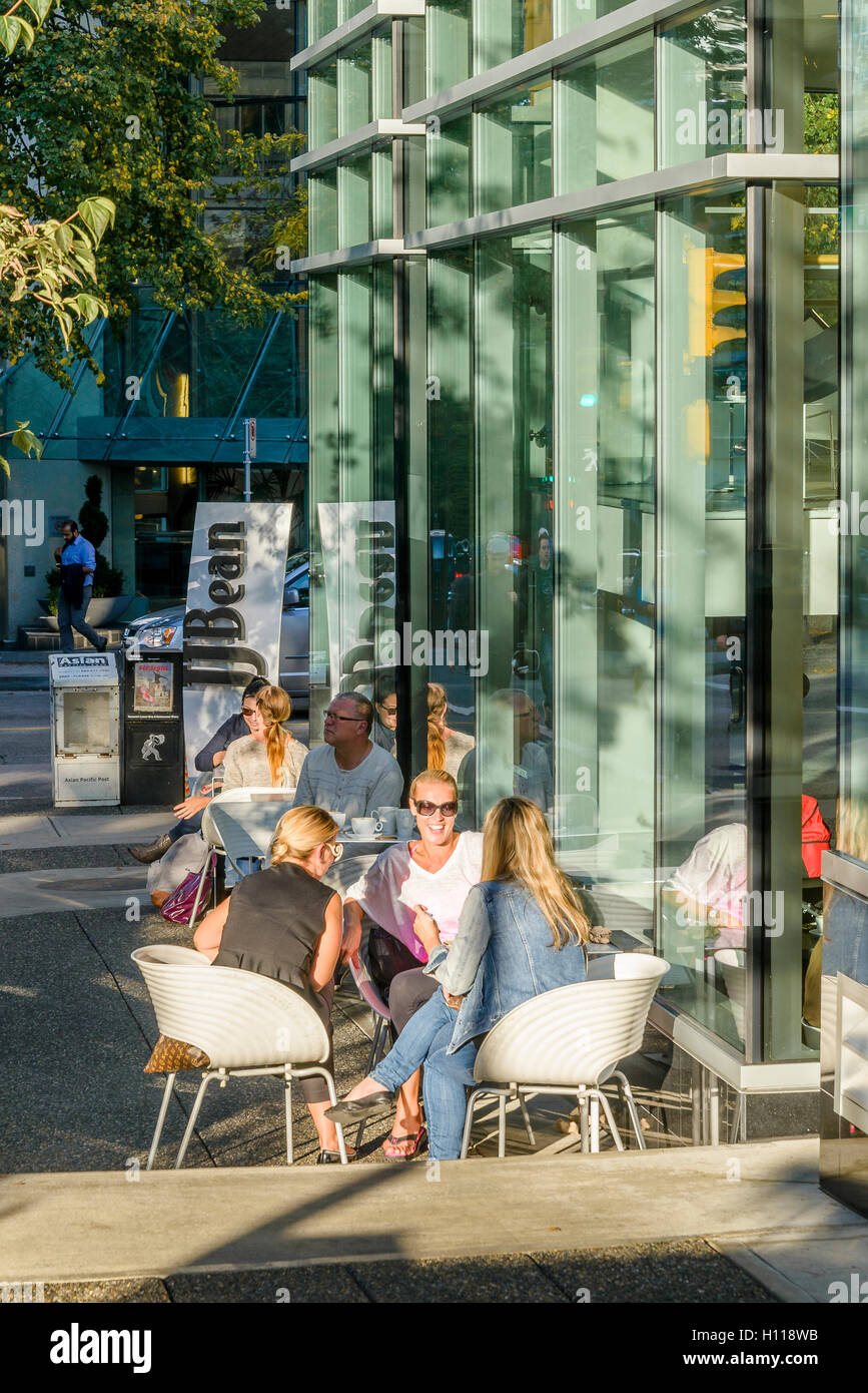 Las mujeres disfrutan de la conversación en la cafetería exterior patio, Vancouver, British Columbia, Canadá Foto de stock