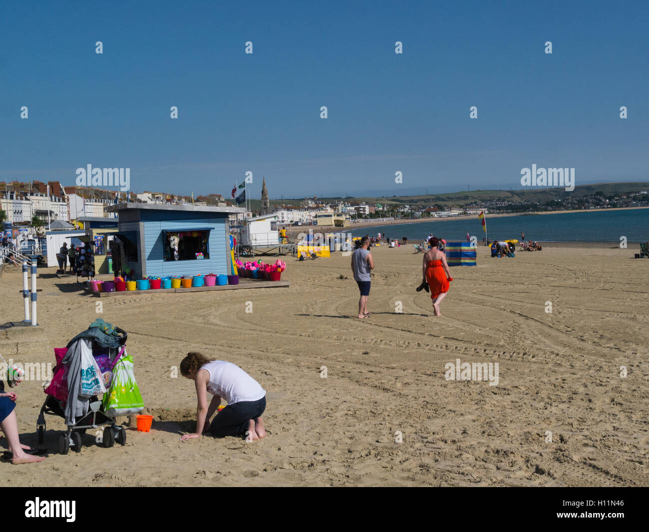 Haciendo que la mayoría de los visitantes de septiembre jornada gloriosa playa de arena dorada de Weymouth con una amplia bahía y coloridas casetas de playa Dorset, Inglaterra Foto de stock